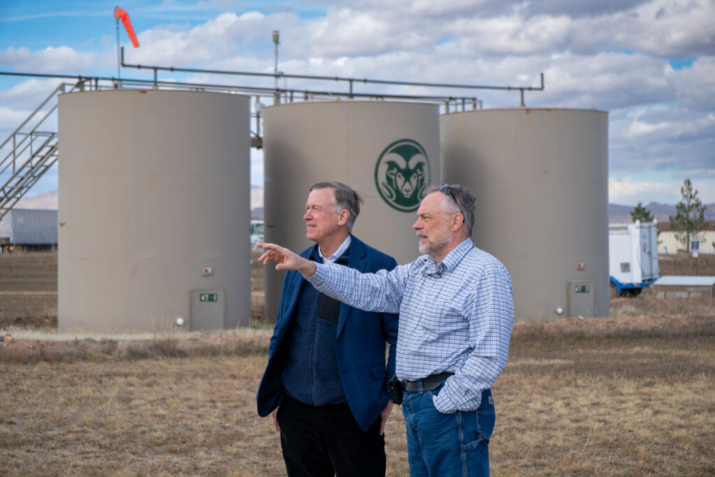 Two men standing in front of storage tanks