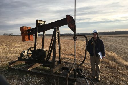 A research stands next to a O&G pumpjack